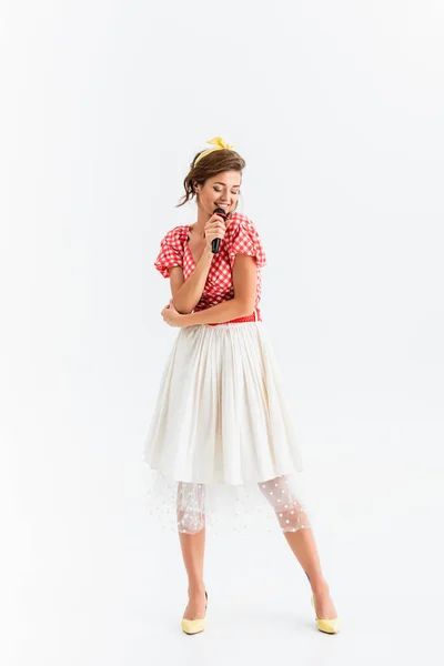 Full length view of pin up woman with microphone singing with closed eyes on white — Stock Photo