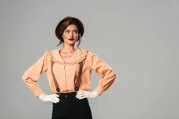 Mujer bonita en ropa vintage de moda posando con las manos en las caderas aisladas en gris - foto de stock