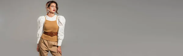 Mujer joven de moda en ropa vintage mirando hacia otro lado aislado en gris, bandera - foto de stock