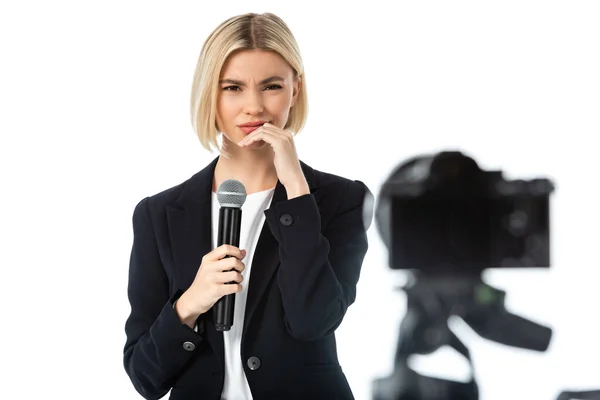 Ancla de noticias descontenta con micrófono cerca de la cámara digital en primer plano borroso aislado en blanco - foto de stock