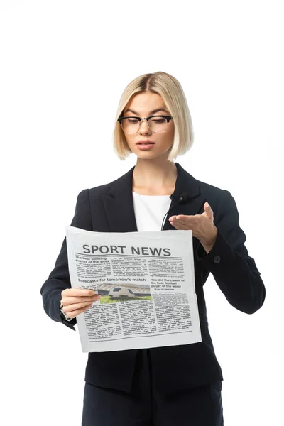 Блондинка в очках, указывающая рукой на газету спортивных новостей, изолированную на белом — стоковое фото