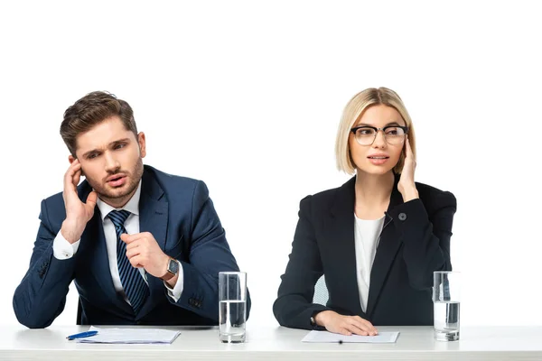 Junge Nachrichtenkommentatoren justieren Kopfhörer, während sie am Schreibtisch isoliert auf Weiß sitzen — Stockfoto