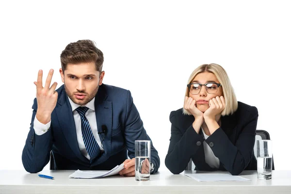 Discouraged broadcaster gesturing near upset colleague at workplace isolated on white — Stock Photo