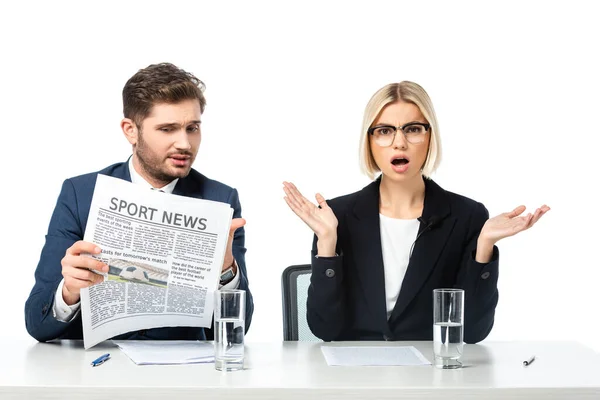 Amazed news anchor gesturing near colleague reading sport news isolated on white — Stock Photo