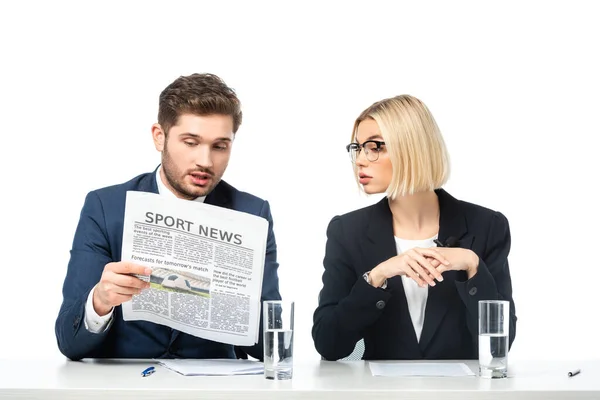 Junger Moderator liest Sportnachrichten in der Nähe blonder Kollegin isoliert auf weißem Grund — Stockfoto