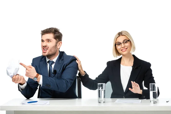 Lächelnde Moderatorin beruhigt irritierten Kollegen beim Zerknüllen von Papier auf Weiß — Stockfoto
