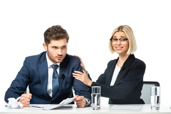 Joven rubia colega calmando enojado colega en el lugar de trabajo aislado en blanco - foto de stock