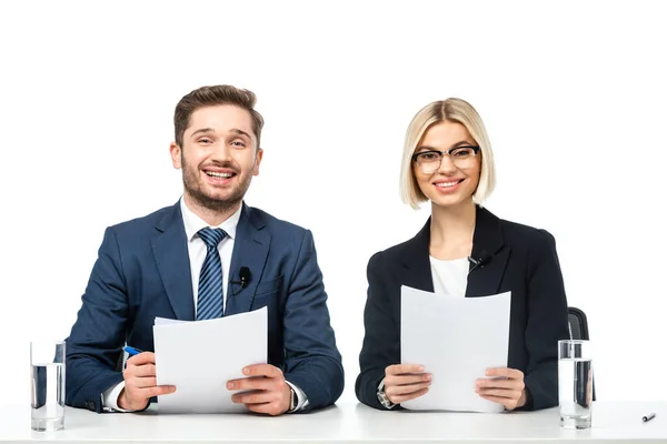 Nachrichtensprecher lächeln in die Kamera, während sie am Arbeitsplatz Papiere isoliert auf Weiß halten — Stockfoto