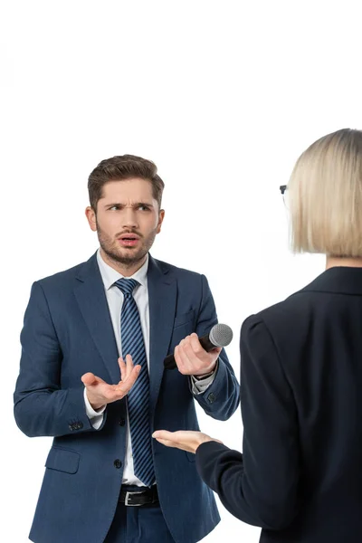 Entmutigte Journalistin gestikuliert mit Mikrofon in der Nähe der blonden Geschäftsfrau bei Interview isoliert auf weiß — Stockfoto