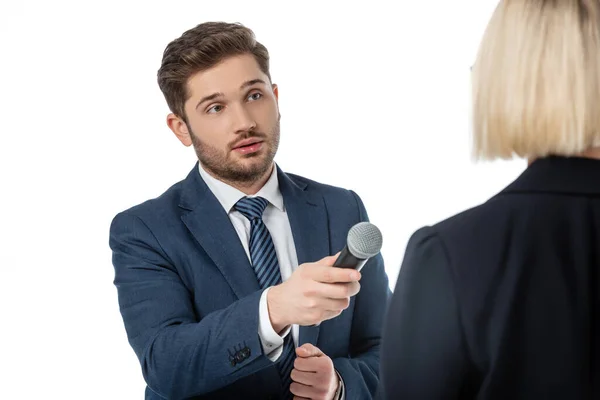 Junge Nachrichtensprecherin mit Mikrofon nimmt Interview von blonder Geschäftsfrau isoliert auf Weiß auf — Stockfoto