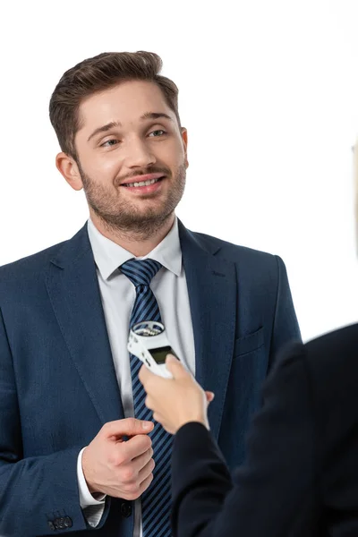 Sonriente hombre de negocios dando entrevista a periodista con dictaphone aislado en blanco, borroso primer plano - foto de stock
