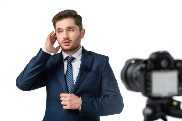 Joven presentador de noticias fijación de auriculares cerca de la cámara digital en primer plano borroso aislado en blanco - foto de stock