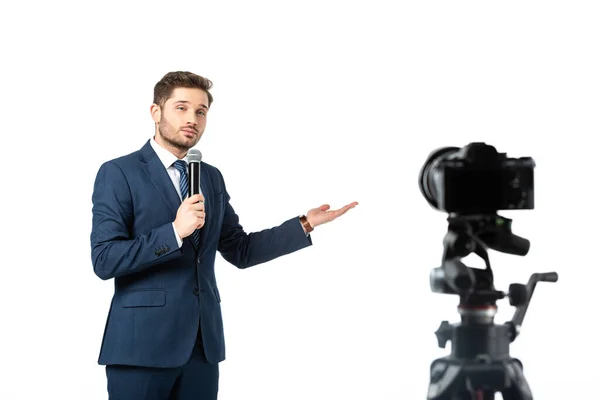 Journalist mit Mikrofon, das mit der Hand zeigt, während er die Digitalkamera isoliert auf weißem, verschwommenem Vordergrund betrachtet — Stockfoto