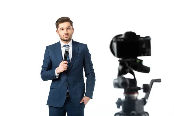 Jeune diffuseur tenant un microphone près de l'appareil photo numérique sur l'avant-plan flou isolé sur blanc — Photo de stock