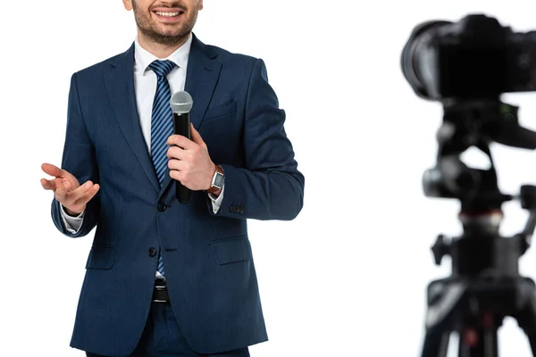 Cropped view of smiling news anchor with microphone near digital camera isolated on white, blurred foreground — Stock Photo