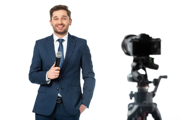 Fröhlicher Nachrichtensprecher mit Hand in Tasche, Mikrofon in der Nähe der Digitalkamera auf unscharfem, auf weiß isoliertem Vordergrund — Stockfoto