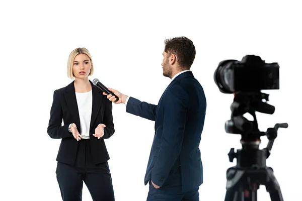 Anchorman with hand in pocket taking interview form blonde businesswoman isolated on white, blurred foreground — Stock Photo