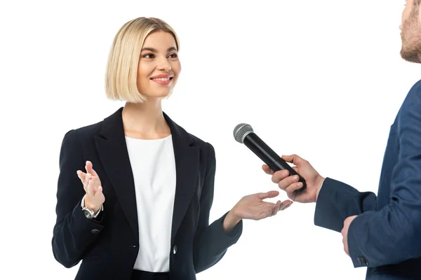 Souriant blonde femme d'affaires parler près intervieweur avec microphone isolé sur blanc — Photo de stock