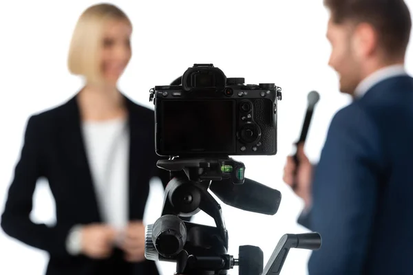 Enfoque selectivo de la cámara digital cerca de periodista tomando entrevista de mujer de negocios aislado en blanco - foto de stock