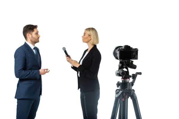 Seitenansicht des Geschäftsmannes im Gespräch während des Interviews mit der blonden Moderatorin isoliert auf weißem, verschwommenem Vordergrund — Stockfoto