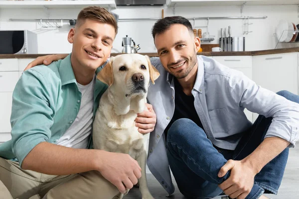 Alegre homossexual homens sorrindo com cão em casa — Fotografia de Stock