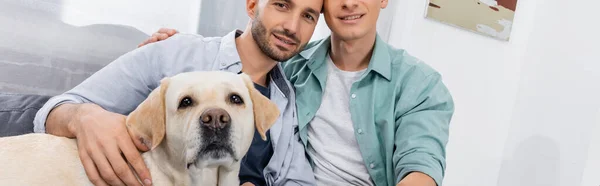 Fröhliches gleichgeschlechtliches Paar lächelt neben Hund, Banner — Stockfoto