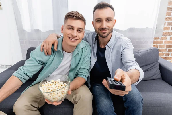 Joyful same sex couple watching movie with tasty popcorn — Stock Photo