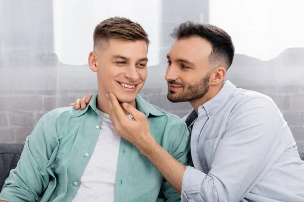 Гомосексуальний чоловік торкається обличчя веселого чоловіка вдома — стокове фото