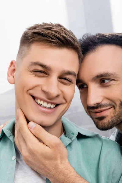 Close up of homosexual man touching face of smiling husband at home — Stock Photo