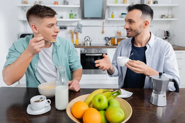 Glücklicher Mann gestikuliert, während er Ehemann beim Frühstück ansieht — Stockfoto