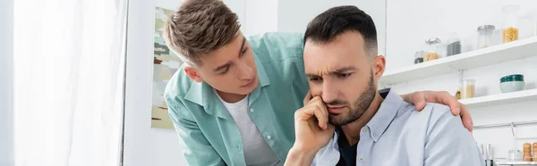 Hombre homosexual molesto mirando preocupado marido, bandera - foto de stock