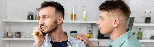 Hombre homosexual preocupado mirando al marido hablando en el teléfono inteligente, bandera - foto de stock