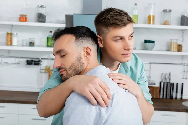 Homosexual man calming while hugging worried husband at home — Stock Photo