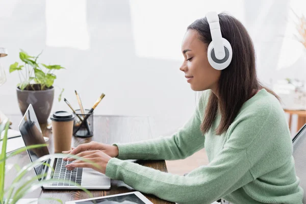 Side view of young african american interior designer typing on laptop at home — Stock Photo