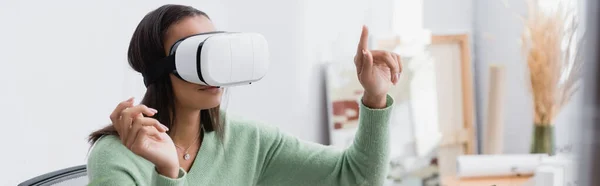 African american architect pointing with finger while gaming in vr headset at home, banner — Stock Photo