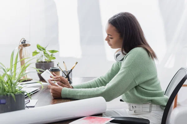 Вид збоку афроамериканського дизайнера інтер'єру з використанням цифрового планшета, сидячи за робочим столом — стокове фото