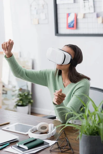 Jovem arquiteto afro-americano gesticulando em fones de ouvido vr em primeiro plano turvo — Fotografia de Stock