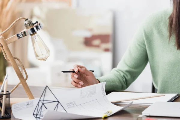 Vista recortada del arquitecto afroamericano sosteniendo lápiz cerca de plano en el lugar de trabajo - foto de stock