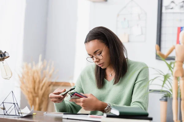 African american interior designer choosing color of material, blurred foreground — Stock Photo