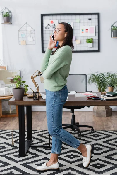 Afrikanisch-amerikanischer Innenarchitekt schaut weg, während er im heimischen Studio mit dem Smartphone spricht — Stockfoto