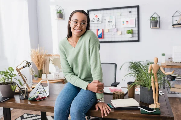 Щасливий афроамериканський архітектор, дивлячись далеко, сидячи на робочому столі вдома — стокове фото