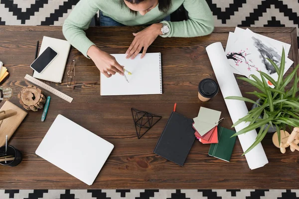 Vista superior del diseñador de interiores afroamericano que trabaja en casa con cuaderno de bocetos y divisor - foto de stock