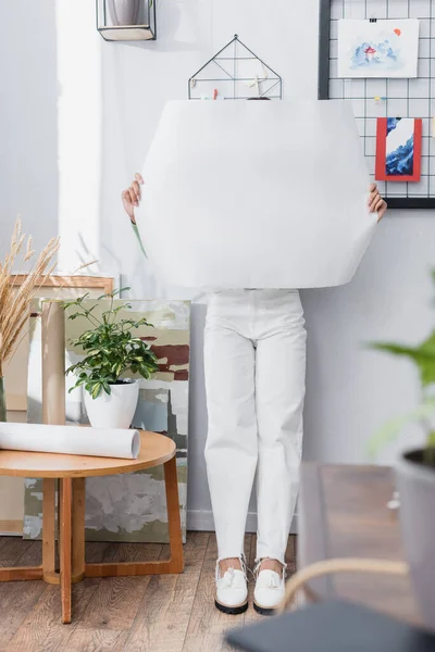 Arquitecto afroamericano oscureciendo la cara con pancarta en blanco en casa, borrosa en primer plano - foto de stock