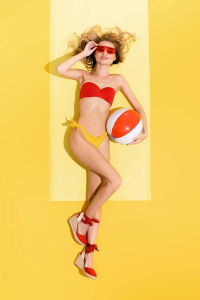 Top view of smiling woman looking at camera while lying with inflatable ball on yellow — Stock Photo