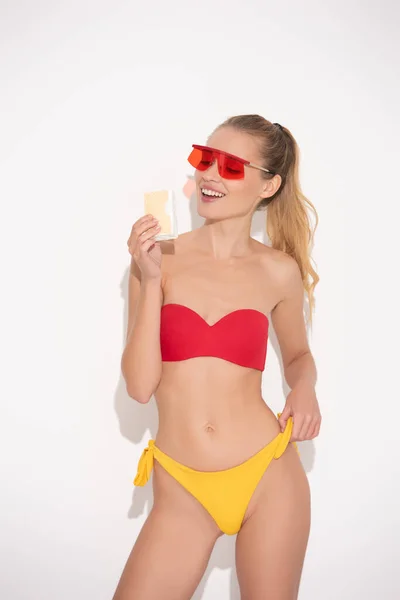 Happy young woman in sunglasses and swimsuit holding delicious ice cream on white — Stock Photo
