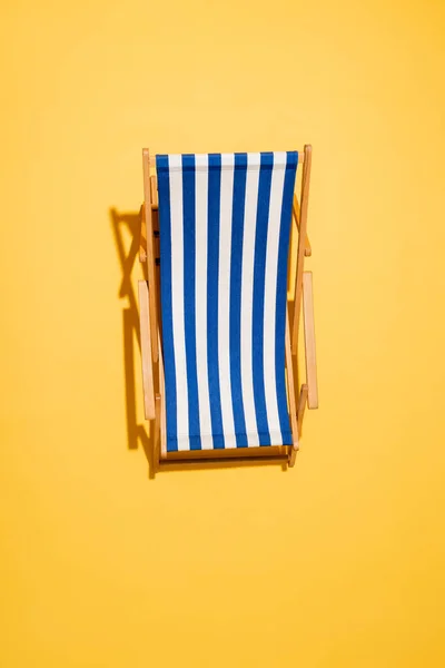 Top view of striped deck chair on yellow — Stock Photo