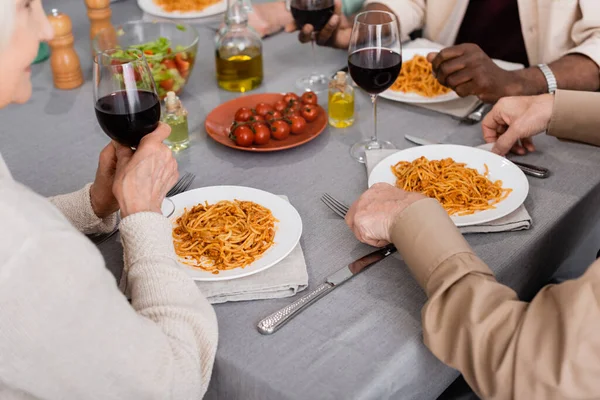 Visão parcial de amigos multiculturais e seniores tendo delicioso almoço juntos — Fotografia de Stock