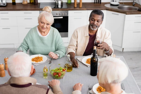 Cheerful and retired interracial friends having lunch together — Stock Photo