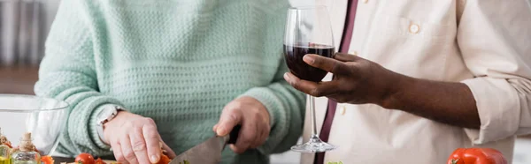 Teilansicht eines afrikanisch-amerikanischen Seniors mit einem Glas Wein in der Nähe seiner Frau, Banner — Stockfoto