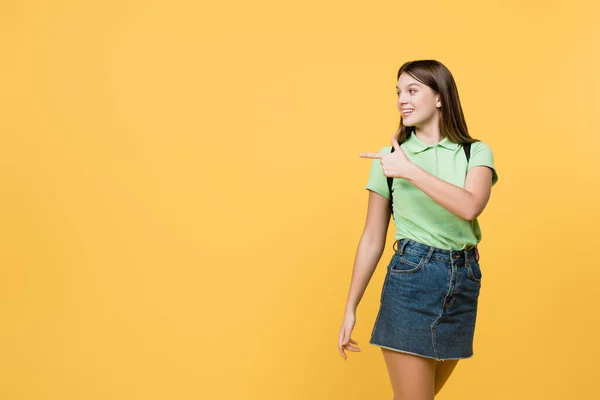 Adolescent joyeux pointant avec le doigt isolé sur jaune — Photo de stock